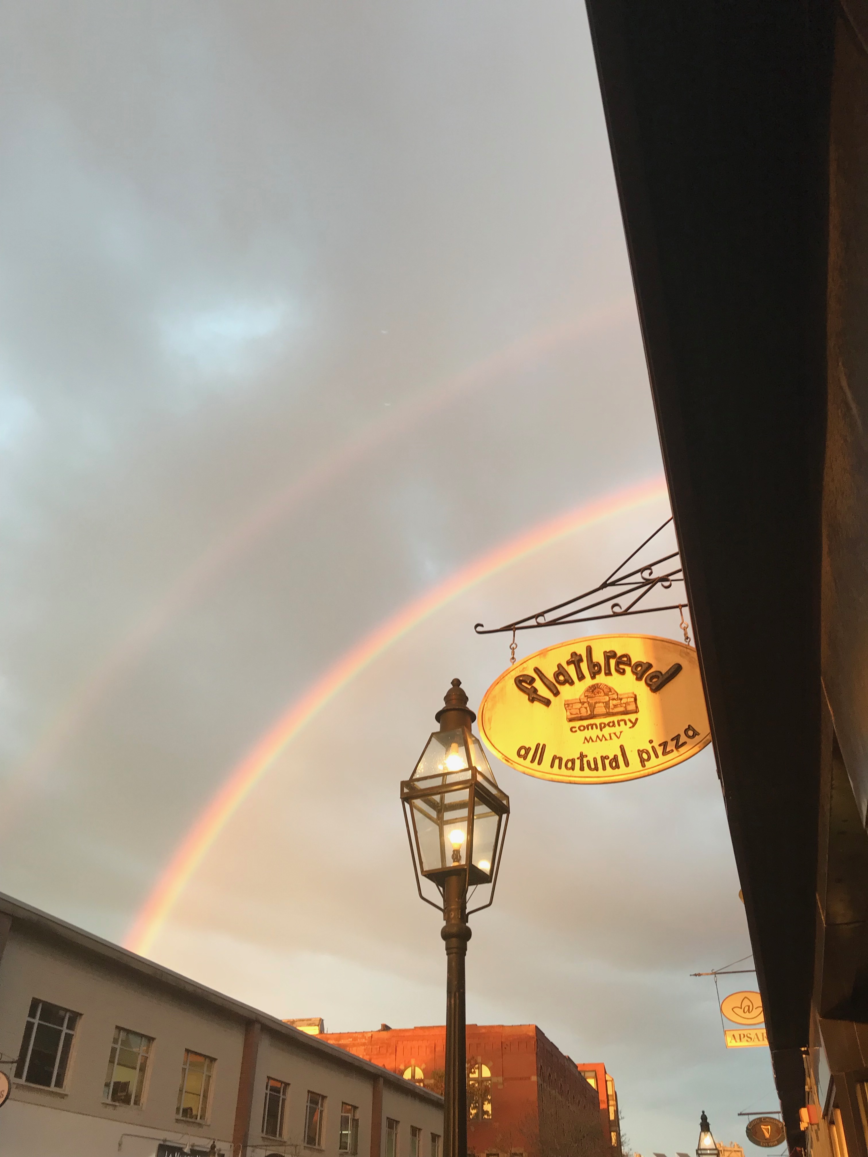 Image of a double rainbow behind Flatbread sign